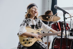 Energetic young girl playing electric guitar and singing into a microphone on stage