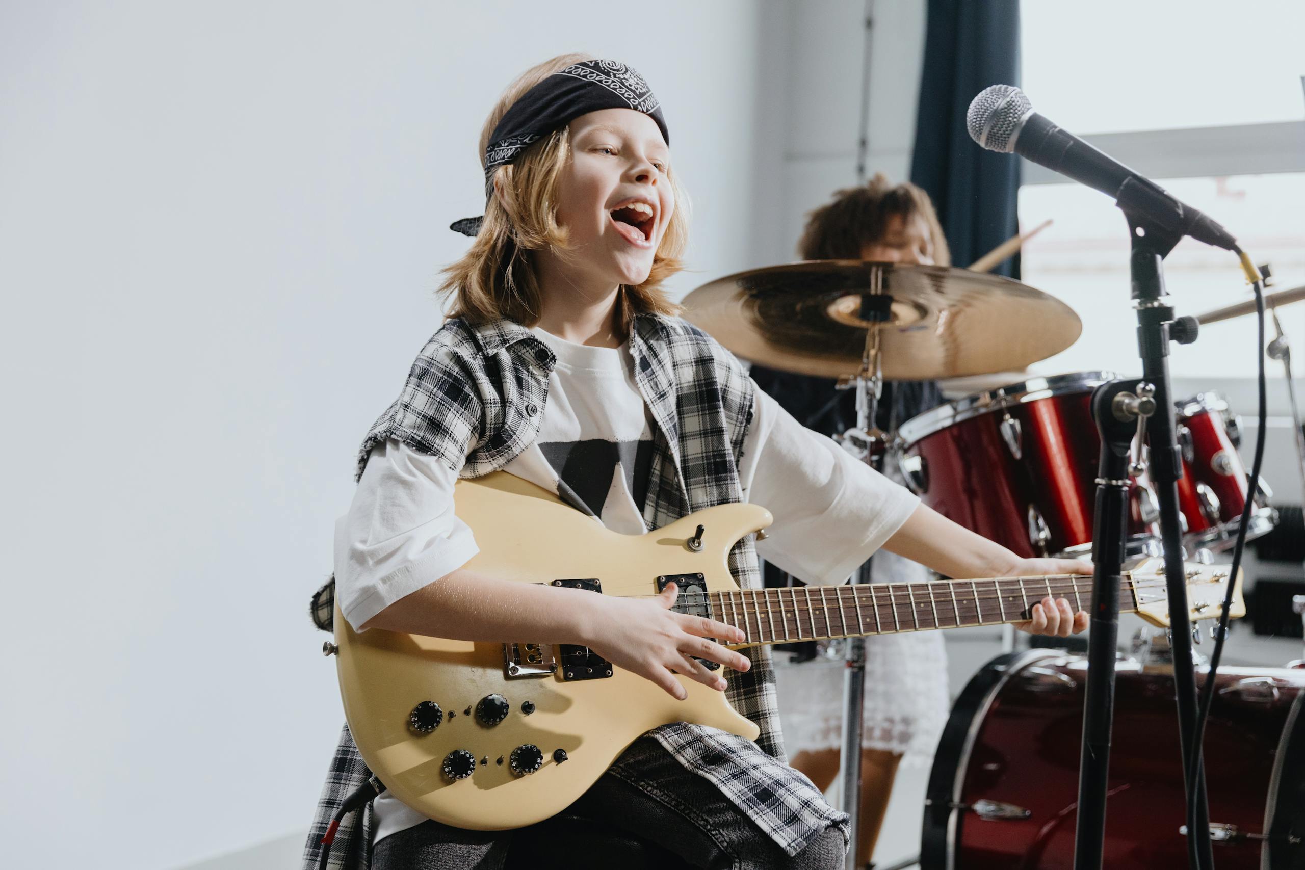 Energetic young girl playing electric guitar and singing into a microphone on stage