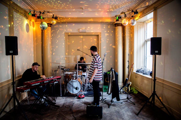 Musicians rehearsing indoors with drums keyboard and vibrant lighting